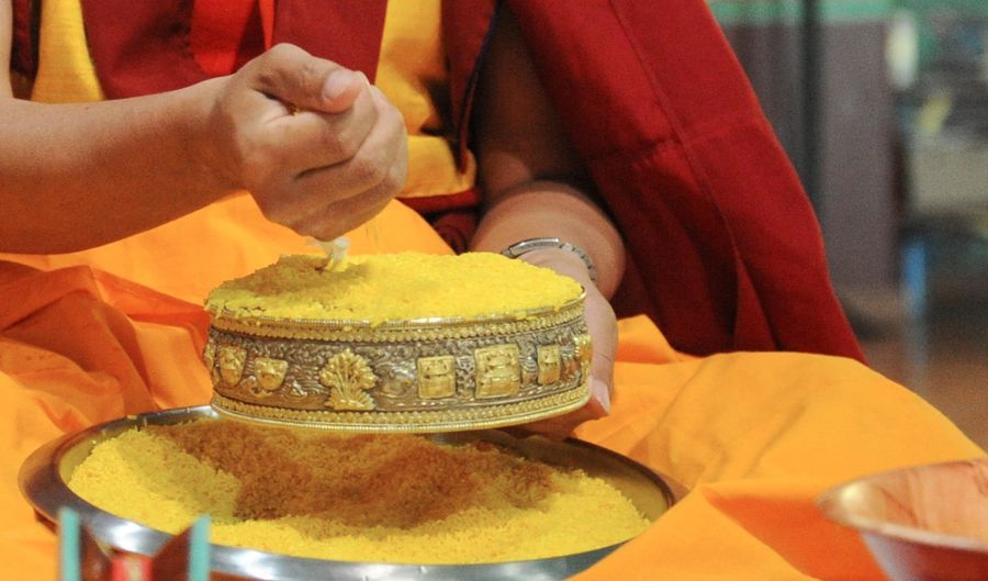 Photo de mains exécutant l'offrande du Mandala